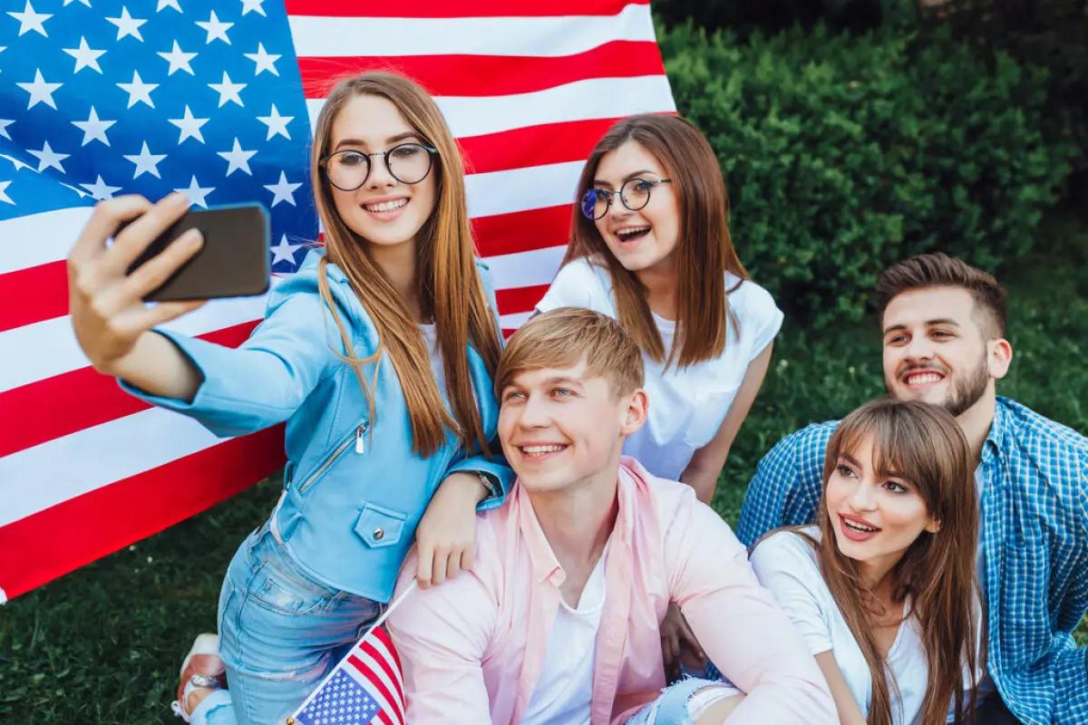 Students in the University, This is the US Independence Day! A group of young Americans doing sephi against the background of the American flag. Mobile phone close up.