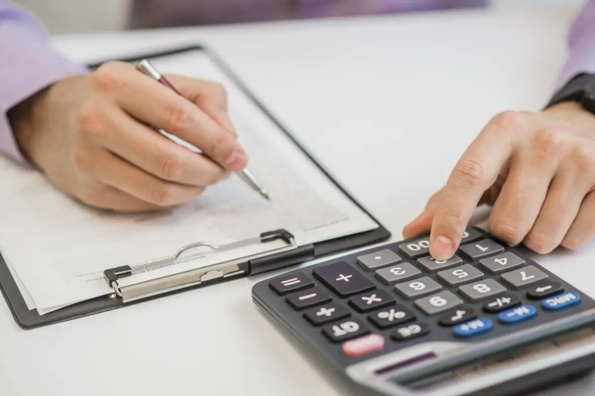 Close-up Of Businessman Calculating Invoices Using Calculator,  