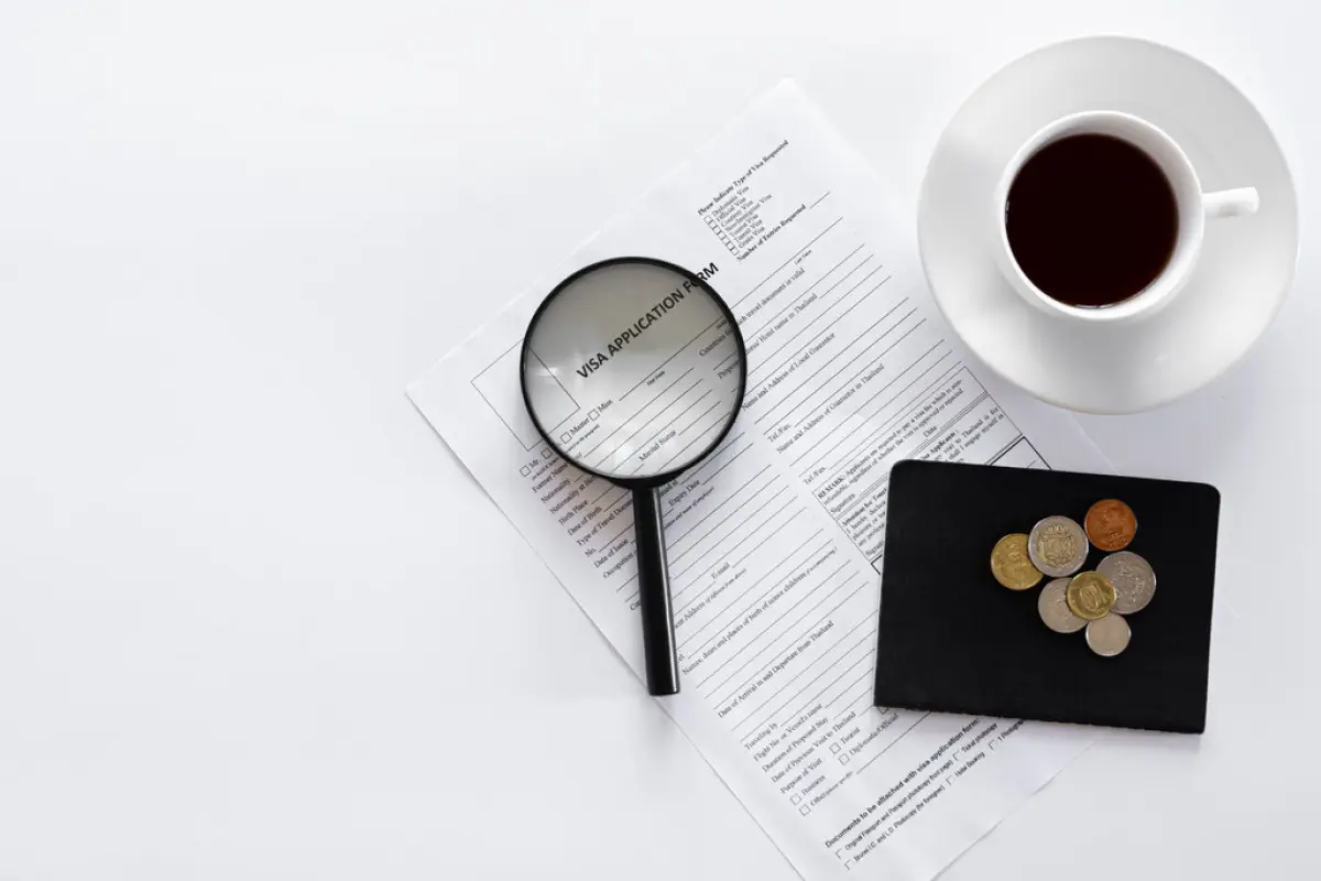 Visa application form, documents and a cup of coffee on a white background., Visa application form, documents, magnifier and a cup of coffee on a white background, the concept of immigration, registration, copy space.