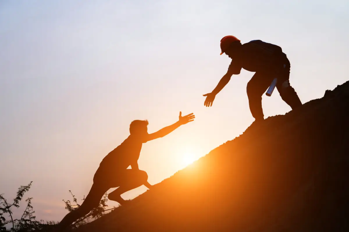 Tourists go up the hill in the sunrise., Tourists go up the hill in the sunrise to shake hands The male traveler shakes the hand of the male traveler who is climbing to the top of the hill