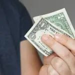 persona sosteniendo un billete de dólar