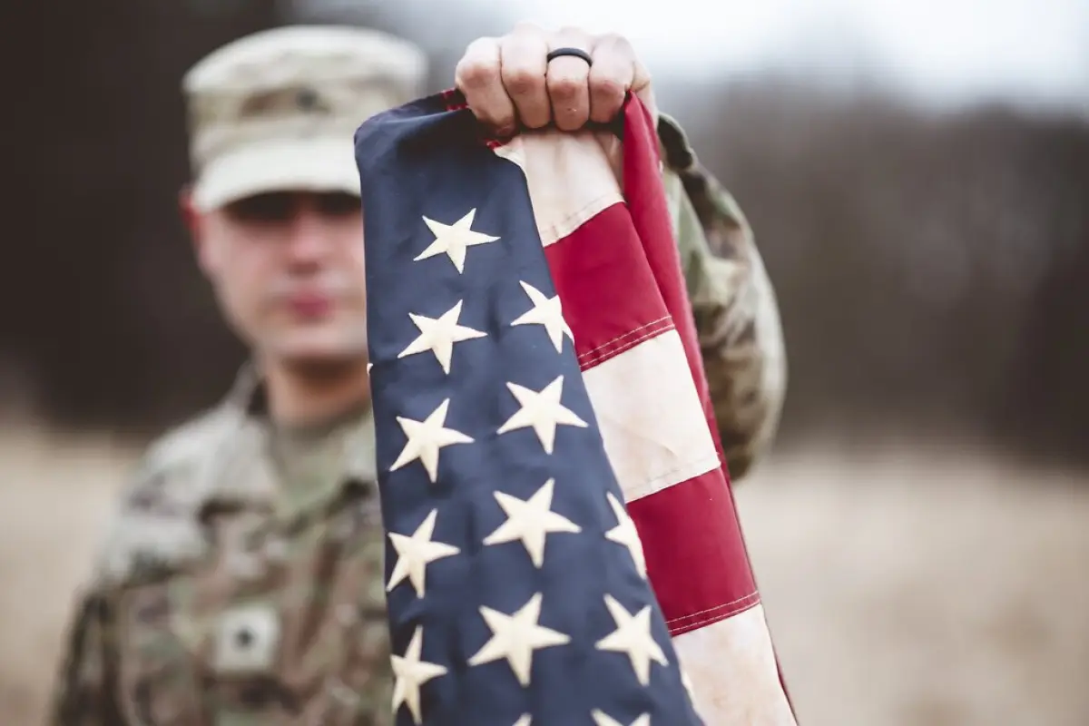 militar estadounidense sosteniendo la bandera de su país