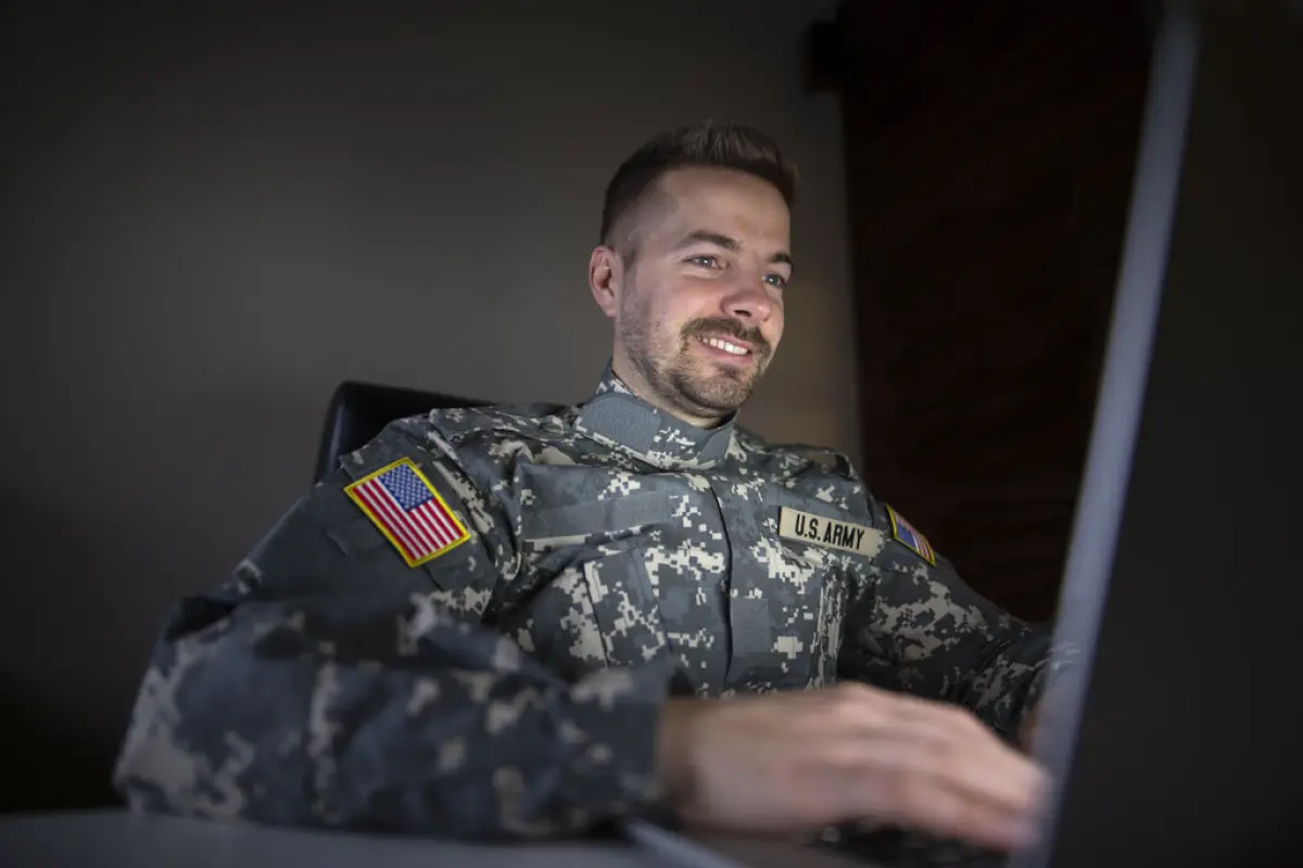 militar sonriente frente a una laptop