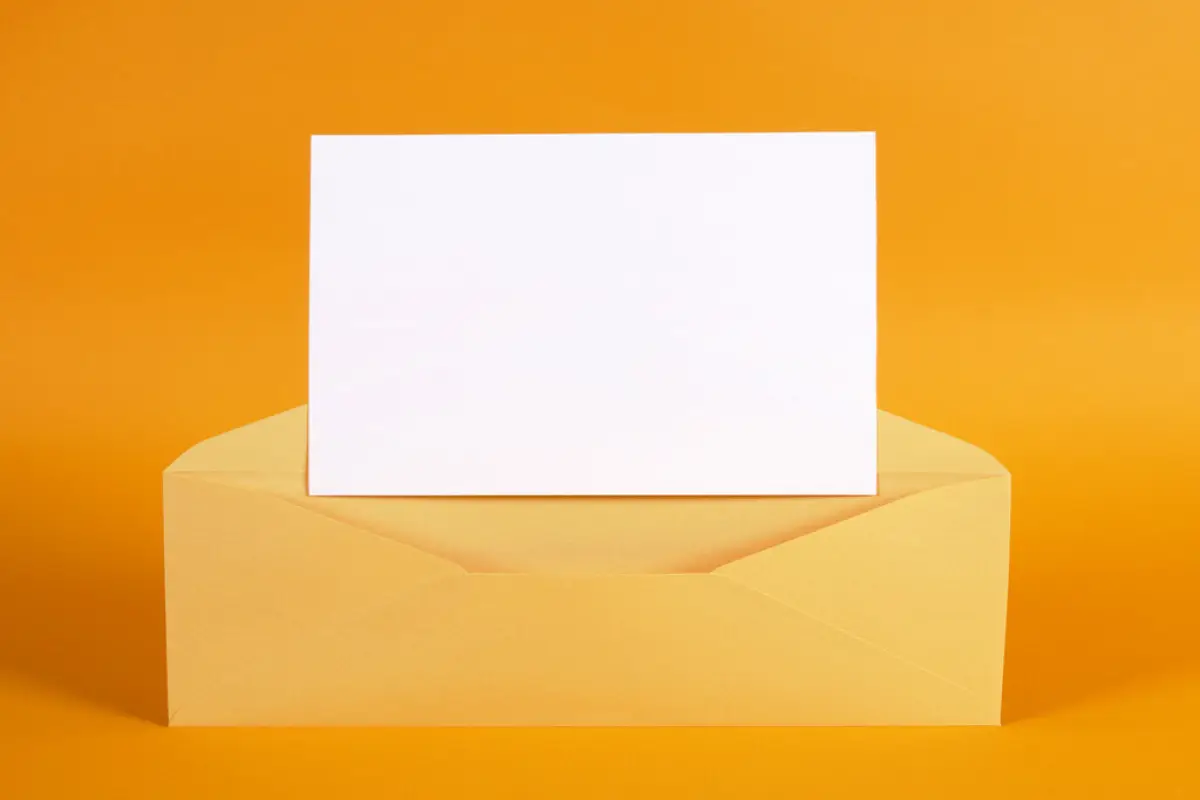 Gold envelope with blank message card, Metallic gold envelope with blank message card letter or invitation isolated on an orange background.  Space for copy.