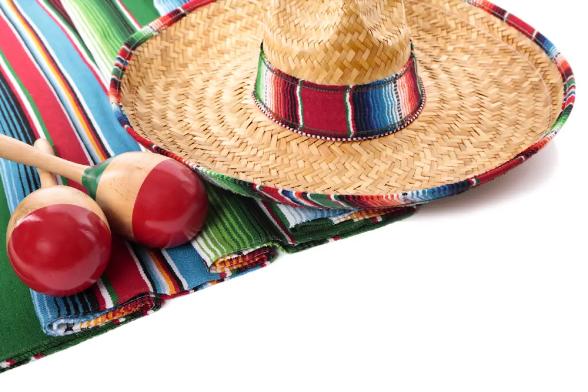 Mexican blanket and sombrero, Traditional Mexican serape blanketor rug with sombrero and maracas isolated against a white background.  Space for copy.