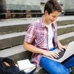 joven estudiante sonriente mirando su laptop