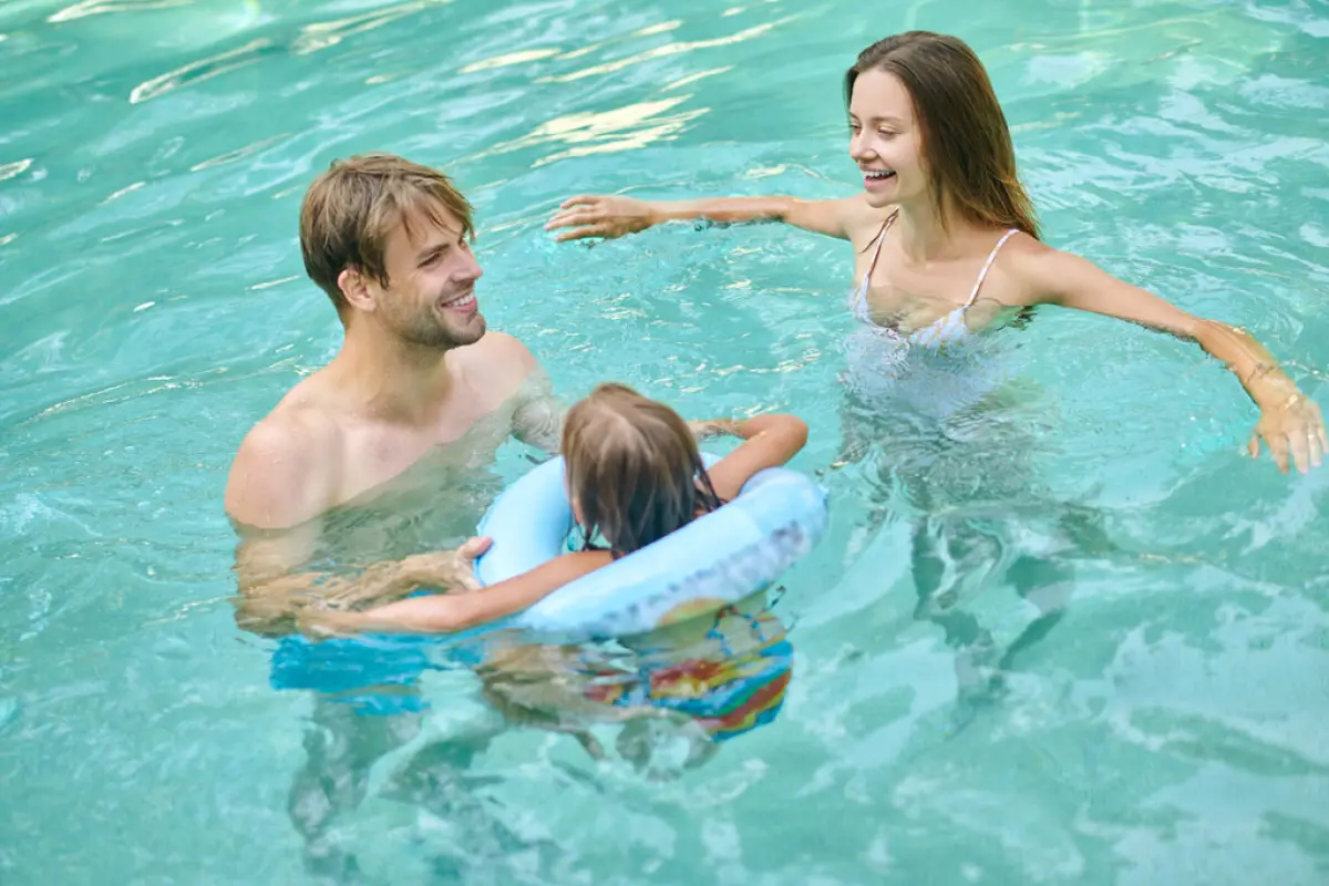 Parents teaching theri daughter to swim and looking involved, At the swimming pool. Parents teaching theri daughter to swim and looking involved